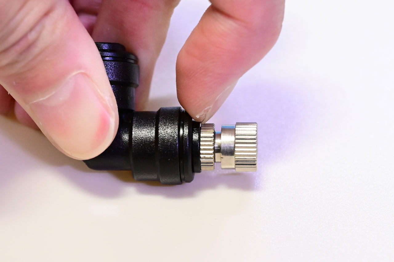 固定リングを押し込んでノズルを外そうとしている