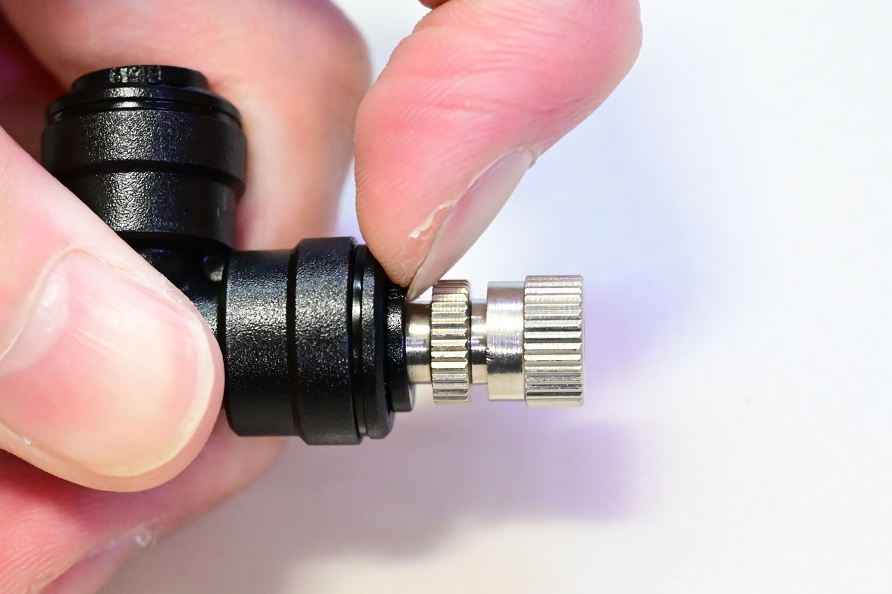 固定リングを押し込んでノズルを外そうとしている、その２